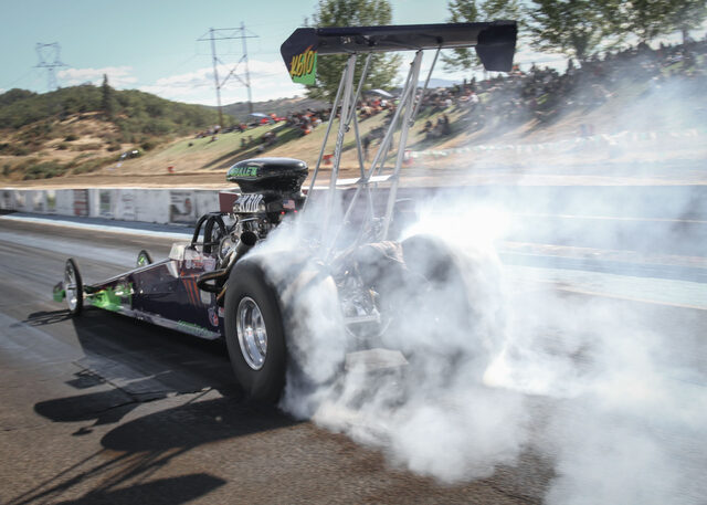 Top Alcohol dragster with exposed engine rolling through the pits